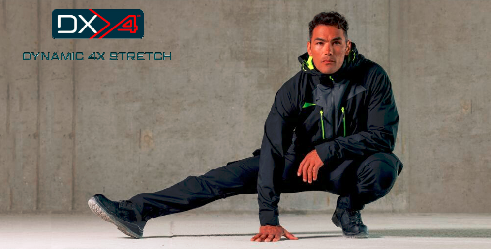 Homem com fato de trabalho desportivo preto com detalhes em cores néon, agachado em frente a uma parede de betão cinzento. No canto superior esquerdo está o logótipo ‘DX4 Dynamic 4X Stretch’.