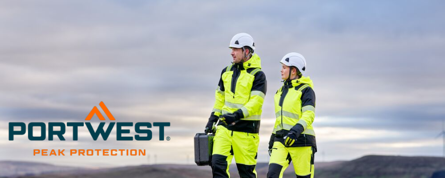 A imagem mostra um homem e uma mulher com roupas de trabalho amarelas e capacetes brancos. Est&atilde;o a caminhar em uma trilha de cascalho. Ao fundo, &eacute; poss&iacute;vel ver uma cadeia de colinas e um c&eacute;u azul com nuvens. O log&oacute;tipo azul e laranja da Portwest est&aacute; localizado no canto inferior esquerdo.