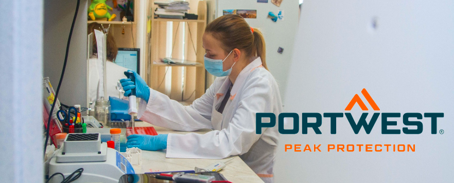 Cientista em laboratório com bata branca, luvas azuis e máscara enquanto trabalha com uma pipeta. Logótipo da Portwest com o slogan ‘Peak Protection’ em primeiro plano.