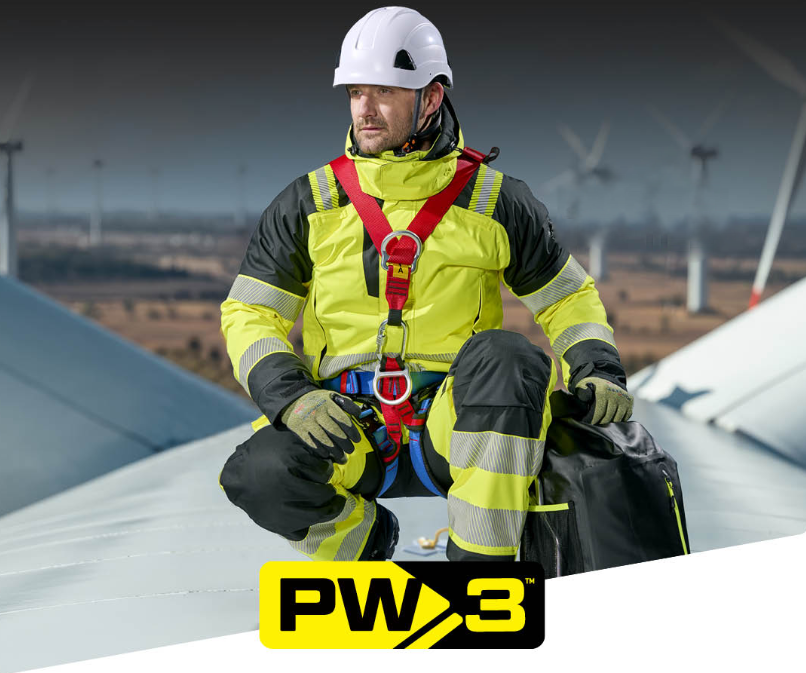 Trabalhador com roupa de trabalho de seguran&ccedil;a Portwest PW3 numa turbina e&oacute;lica. Um link para a cole&ccedil;&atilde;o PW3 est&aacute; inclu&iacute;do.