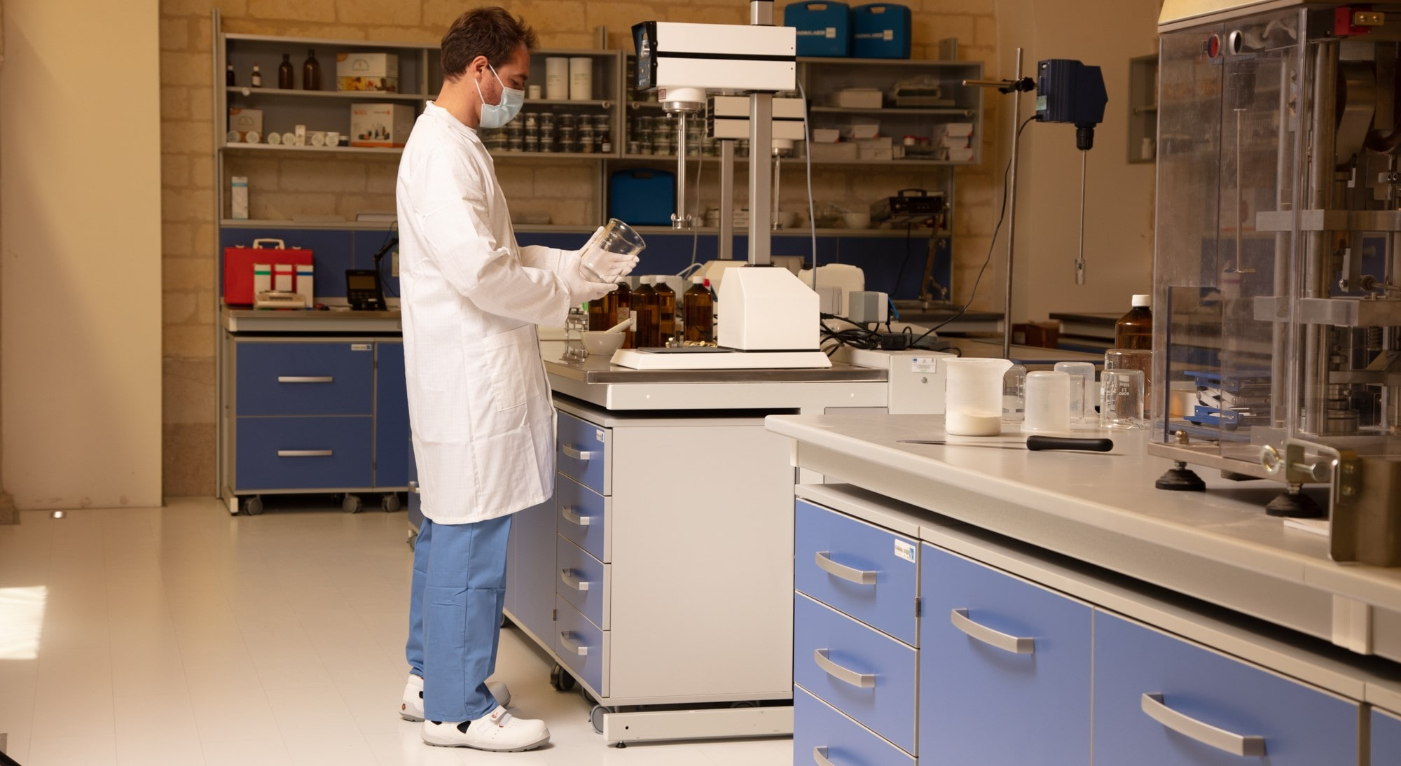 Técnico de laboratório em um jaleco branco e roupa de proteção antiestática no trabalho no laboratório com um link vinculado ao jaleco antiestático.